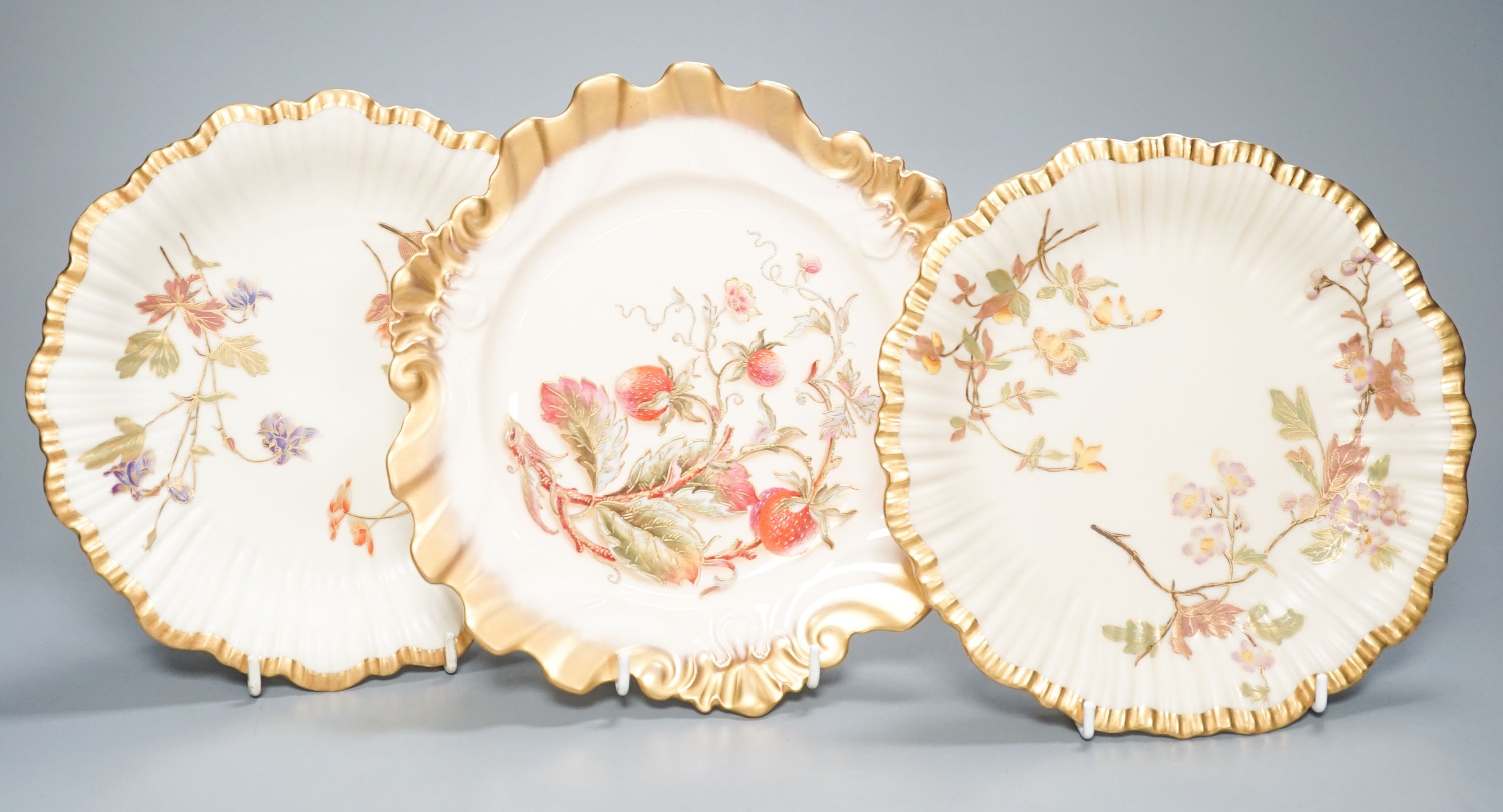 A Royal Worcester fine moulded plate painted and gilded with Strawberries by William Hale, signed WH verso, date mark 1890 and a pair of ivory moulded plates painted and gilded with tree branches, largest diameter 23cm